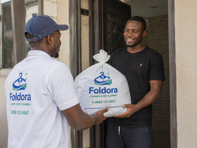 Foldora laundry staff delivering freshly cleaned clothes to a customer in Utako, Abuja